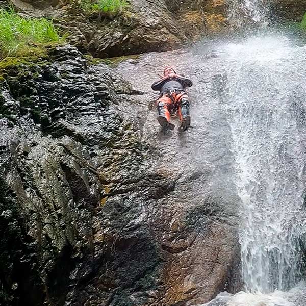 Hombre bajando por tobogán en río haciendo barranquismo nivel avanzado