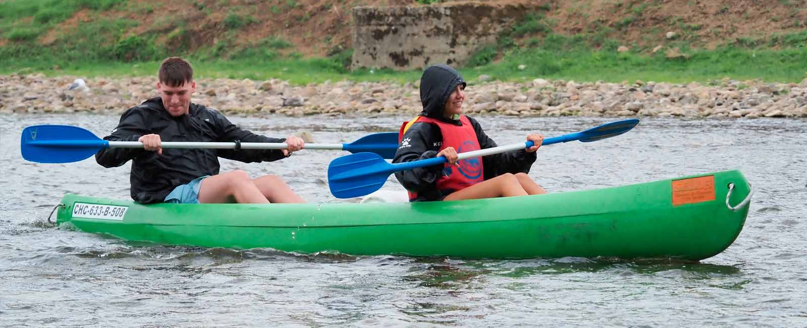 Pareja en canoa haciendo el descenso del Sella lloviendo