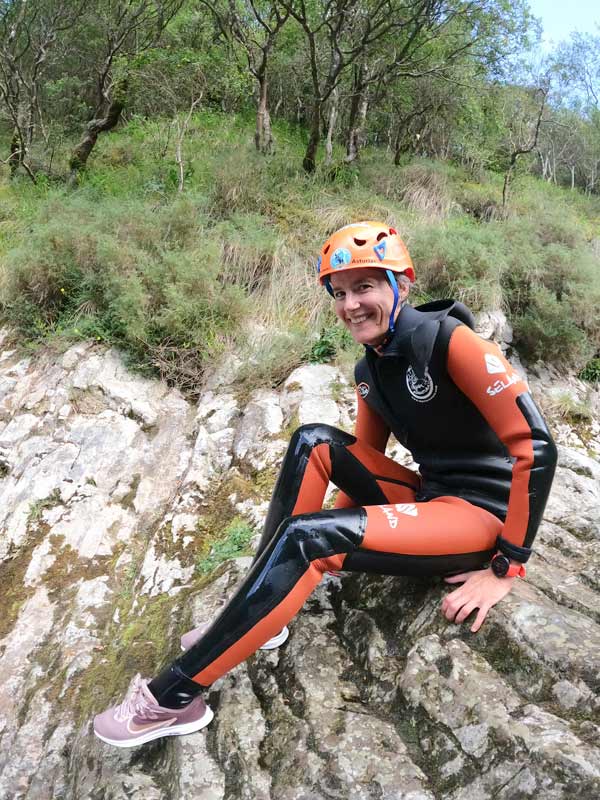 Persona equipada para hacer barranquismo con casco, y neopreno