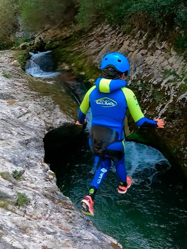 Niño haciendo barranquismo saltando a poza en río